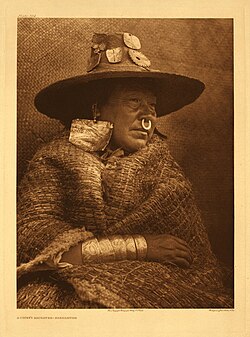A chief's daughter from the Nakoaktok nation. Shown wearing copper headpieces, abalone earrings, nose ring, and inscribed metal bracelets