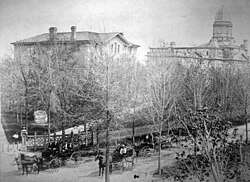 The northwest corner of The Diag around 1873, showing the university's gate, the Law Building (1863–1950) and University Hall (1872–1950)