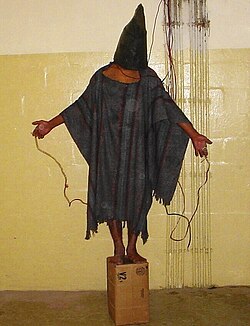 At Abu Ghraib prison, members of the US Army and the CIA physically, sexually, and psychologically tortured and abused prisoners in US custody. The image of The Hooded Man symbolized the scandal.