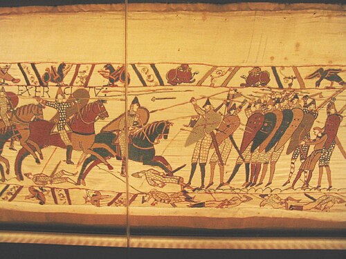 Norman cavalry armed with lances attacks the Anglo-Saxon shield wall. Notice the dominance of the spearmen in the front line of the formation. In the back of the formation there is one warrior armed with a battle-axe, one archer, and one javelineer. There are javelins in mid-flight and slain soldiers pierced with javelins on the ground