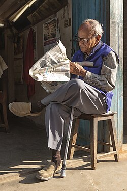 Old man reading newspaper at Basantapur