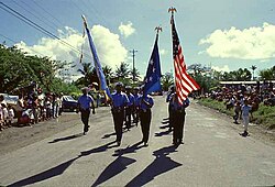 Palau District Constabulary in a parade; the TTPI flag is being carried at the center.