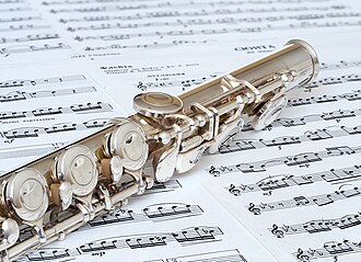 Close-up of part of the body and the C-foot joint. The instrument features plateau keys with Y-arms, trill keys, and soldered tone holes. The image depicts the D-key adjustment screw, and needle springs.[20]