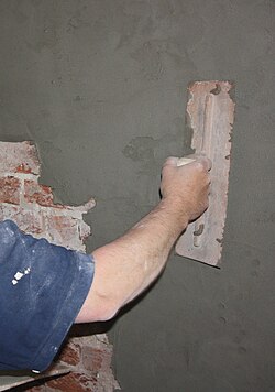 Application of a sand:cement render to a wall as part of a rising damp treatment