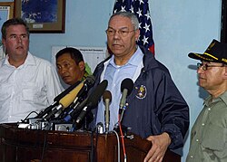 Powell in Banda Aceh speaking on United States's involvement in recovery efforts following the 2004 Indian Ocean earthquake and tsunami with Alwi Shihab wearing green