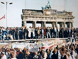 People standing on top the Berlin Wall during its fall in 1989 in front of the Brandenburg Gate
